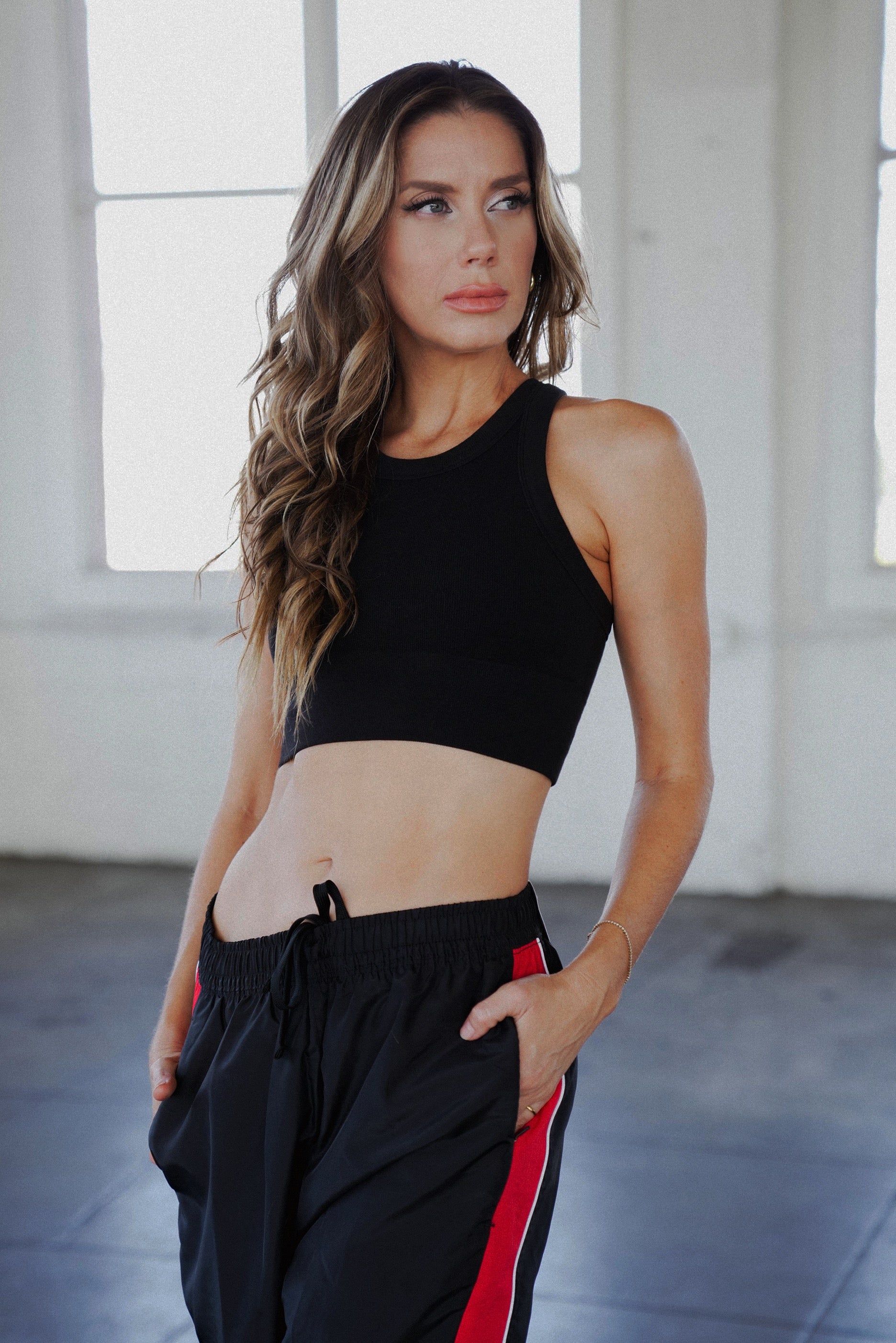 Ashley in black crop tank with black athletic pants on with hands in pocket